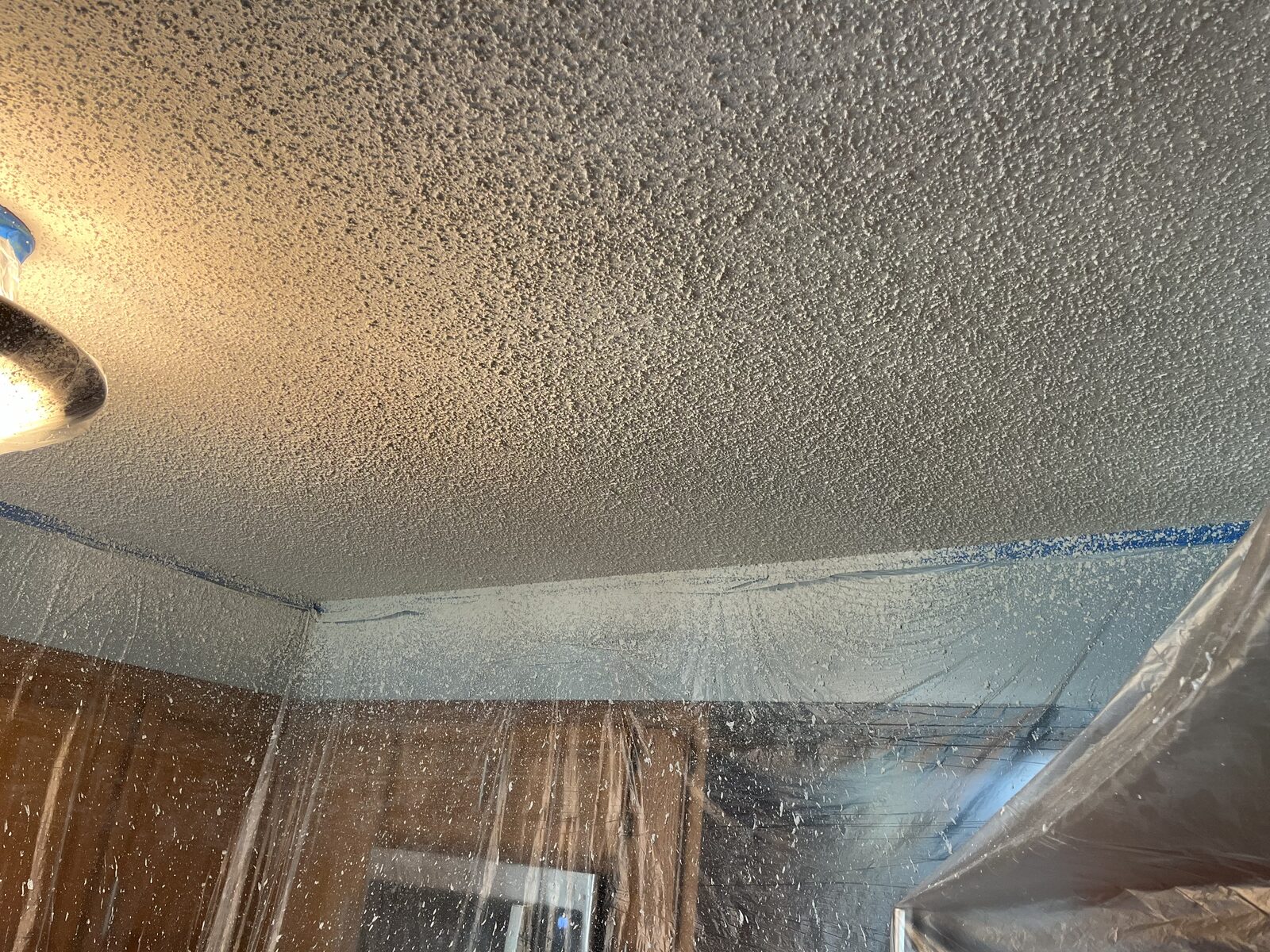 Freshly painted popcorn ceiling with walls and floors fully masked in plastic sheeting and painter's tape