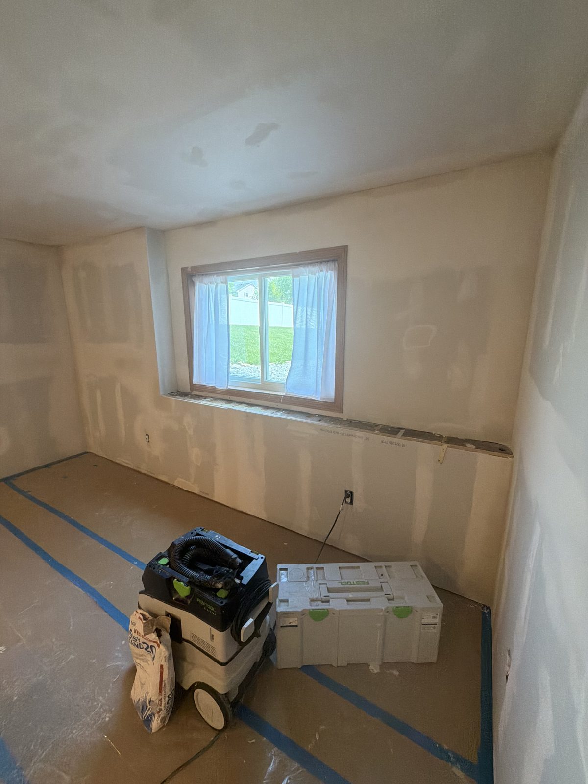 Bedroom with drywall taped, mudded and sanded smooth, floor protected and a dust extractor in the corner