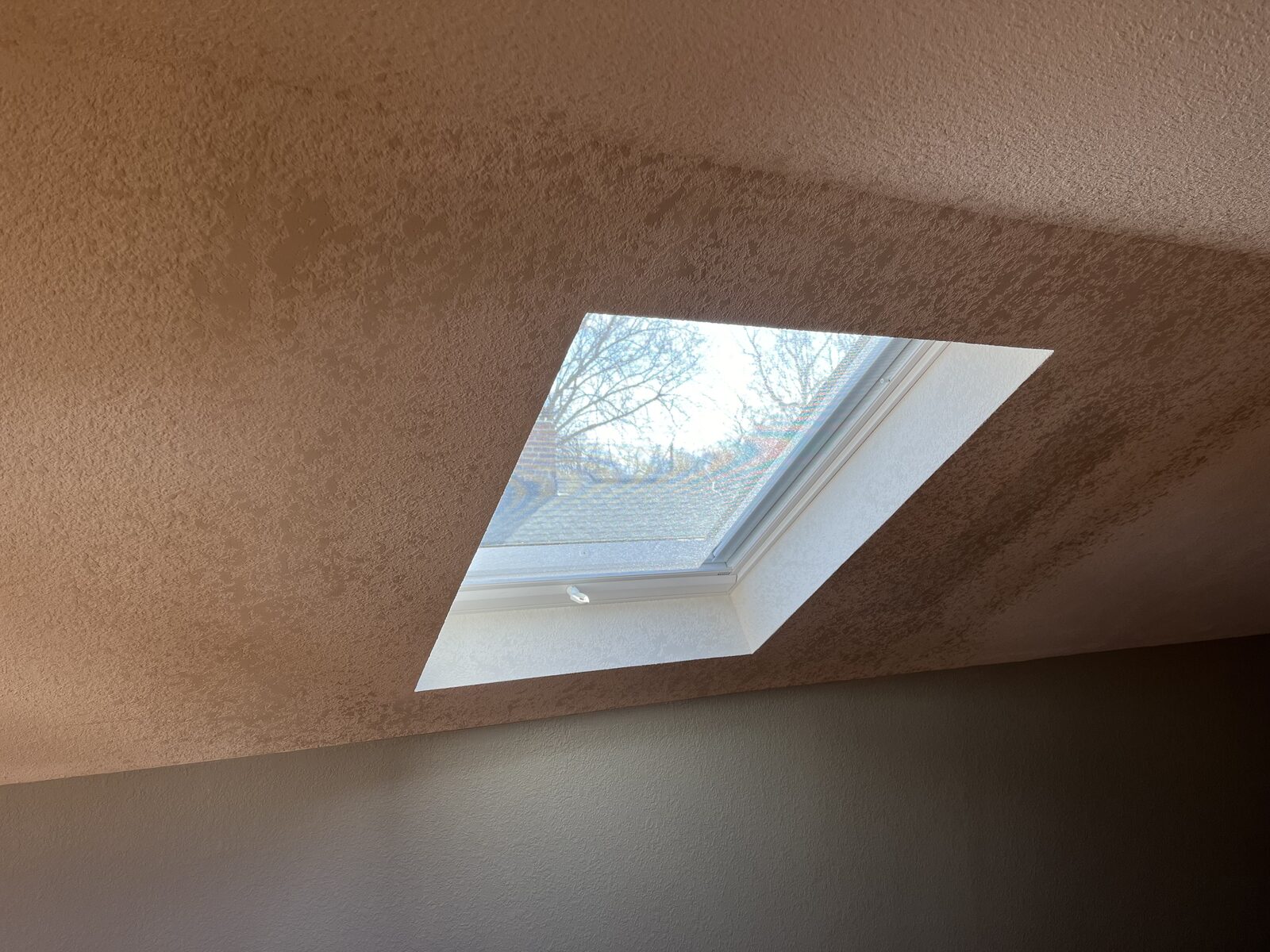 Angled view of a finished skylight well with clean drywall corners blended into the existing textured ceiling