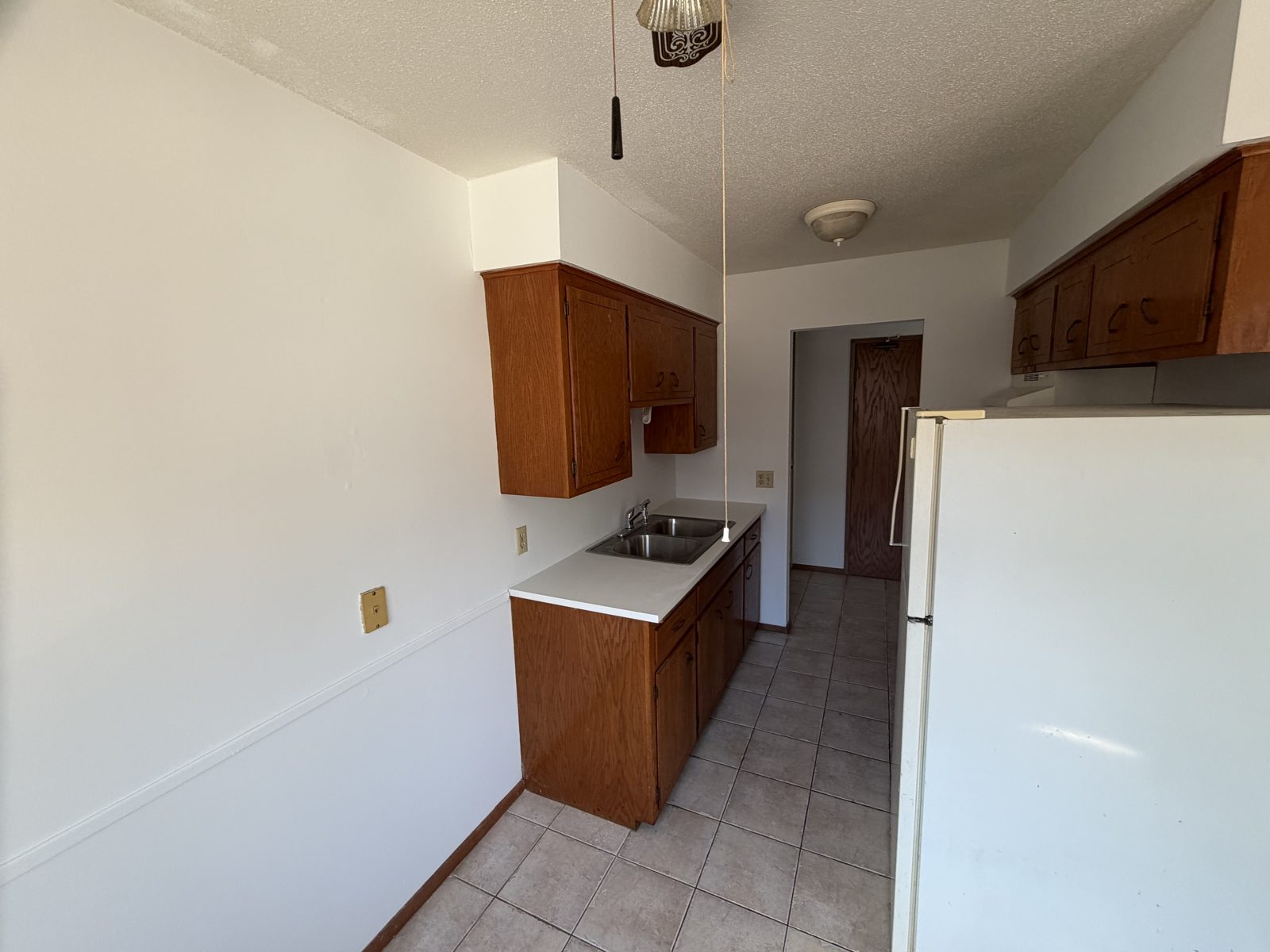 Galley kitchen with wood cabinets and freshly painted walls and ceiling after a rental turn repaint